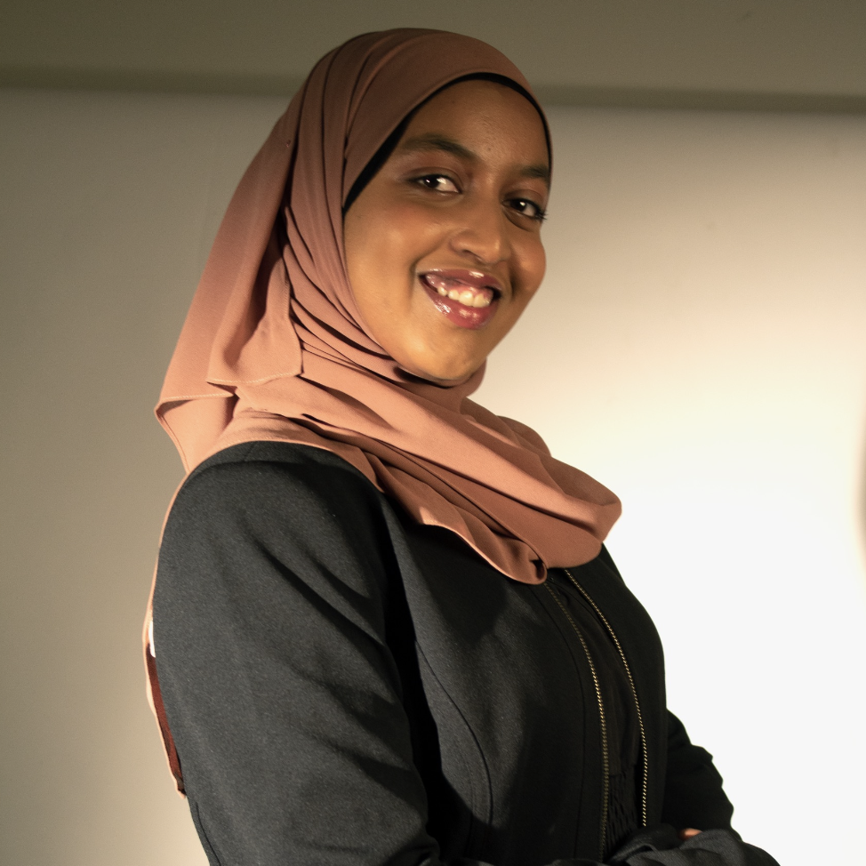eman omer teacher wearing brown scarf and black shirt smiling